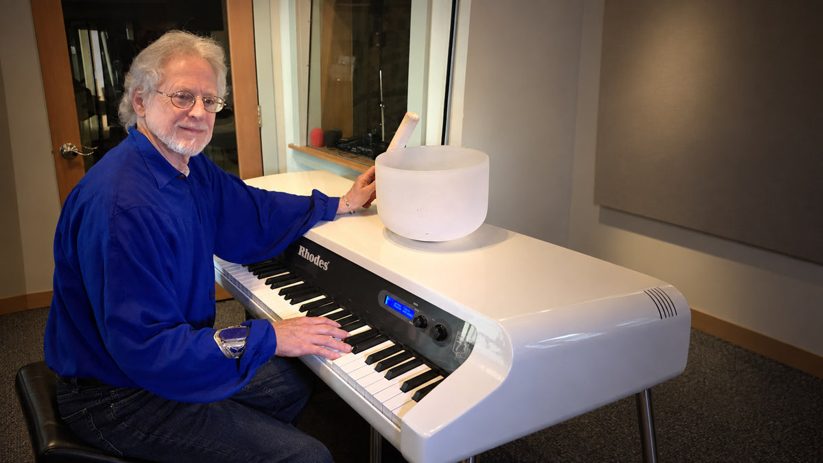 Steven Halpern seated at his classic white Rhodes piano with a crystal singing bowl